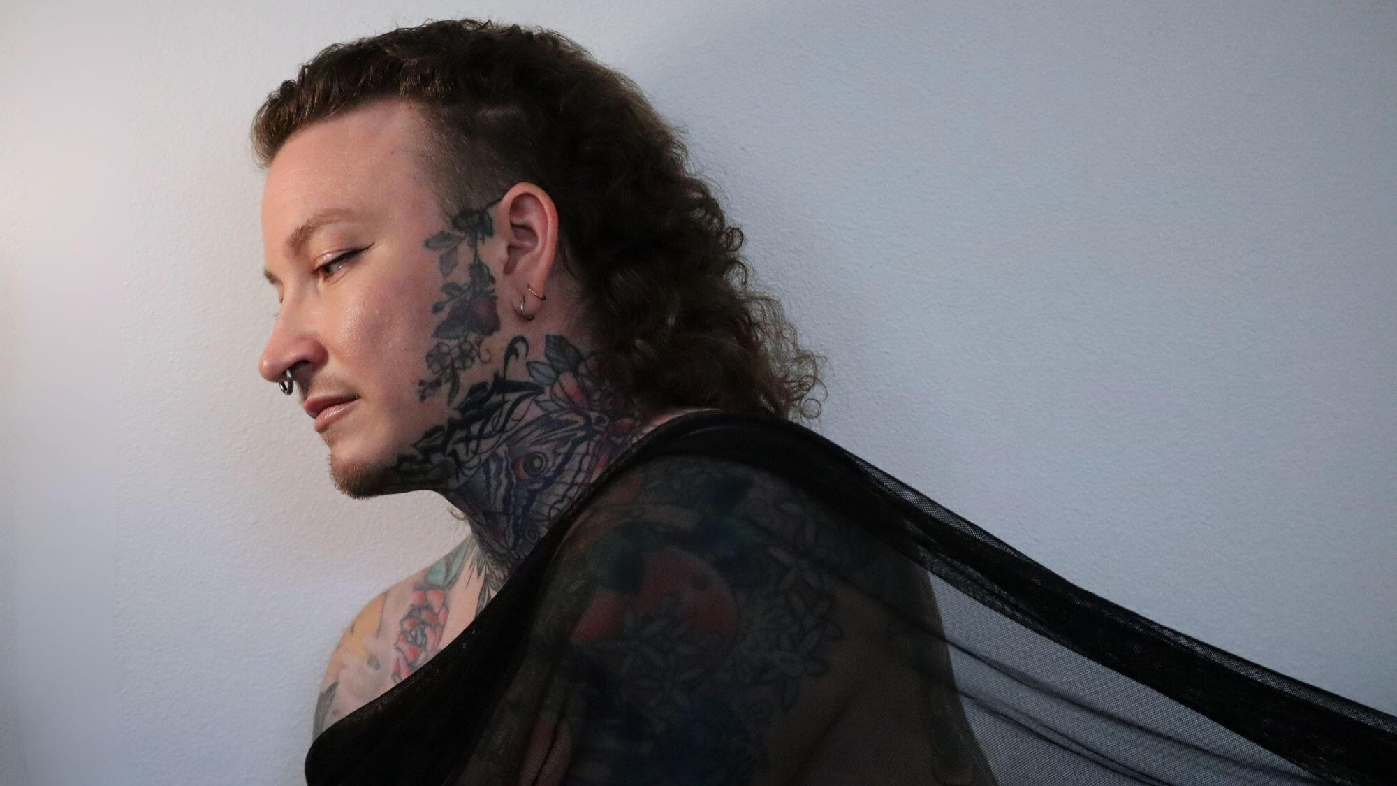 Profile portrait of Alec with a black sheer fabric draped over her shoulders.